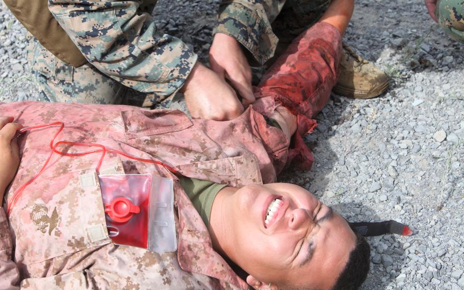 A person administers aid on another with a fake wound.