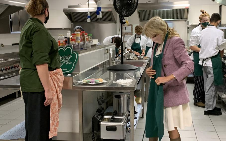 First Lady Jill Biden puts on an apron during a visit to a cooking class at Naval Support Activity Naples Middle/High School, Nov. 1, 2021. Biden helped students prepare ravioli during the visit.