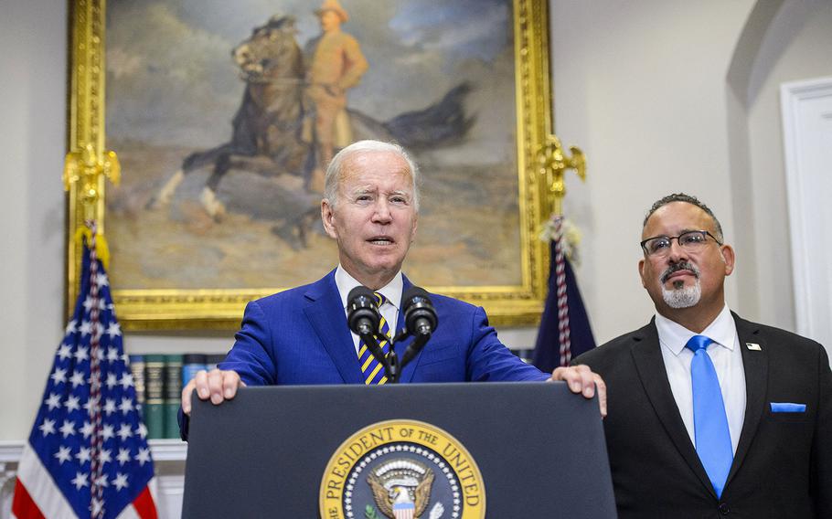 President Joe Biden speaks as Secretary of Education Miguel Cardona looks on after Biden announced a federal student loan relief plan in the Roosevelt Room at the White House in Washington, D.C. on Wednesday, Aug. 24, 2022. 