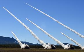 Missile contrails streak across a blue sky. 