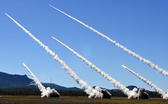 Missile contrails streak across a blue sky. 