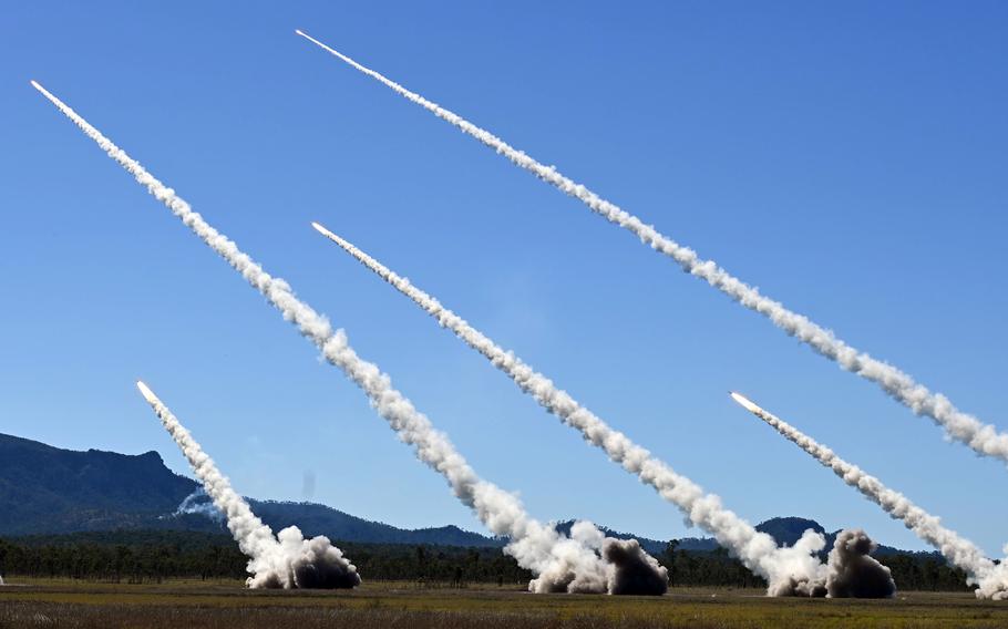 Missile contrails streak across a blue sky. 