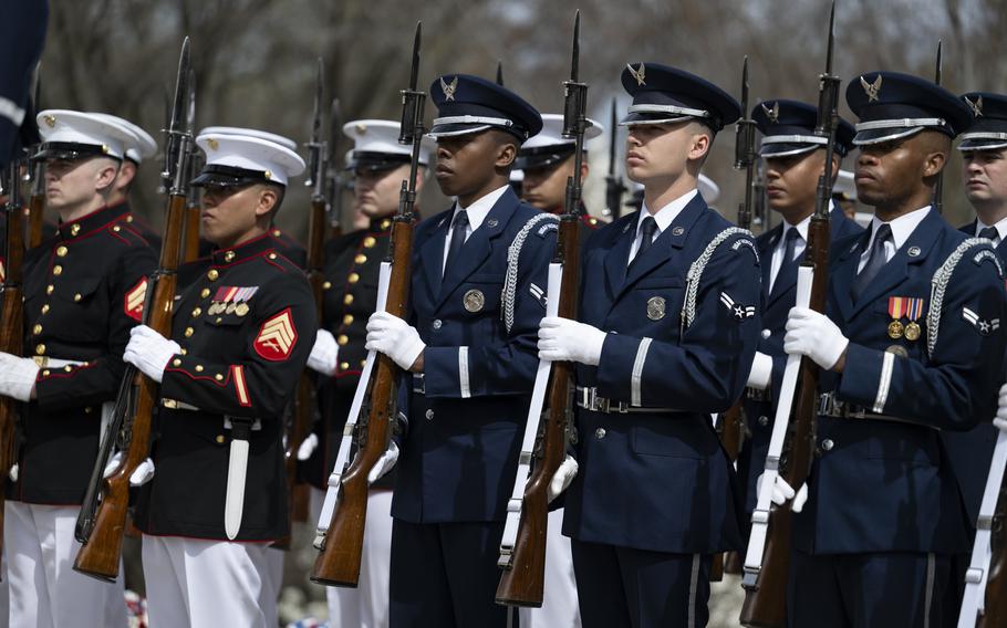 Service member stand in formation with weapons