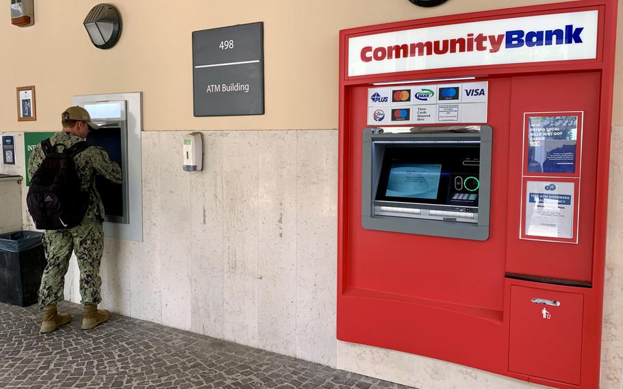 A uniformed service member performs a transaction at an ATM near a Community Bank ATM.