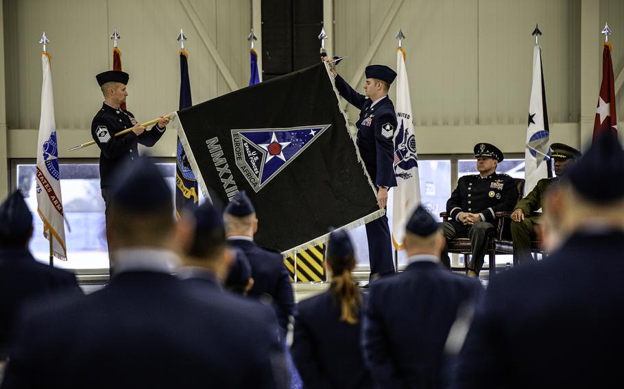 U.S. Space Force guardians unfurl the unit banner of the newly established U.S. Space Forces Europe and Africa component command Dec. 8, 2023, during a ceremony at Ramstein Air Base, Germany. The roman numerals signify the year 2023, representing the year the unit was activated, while the dark background symbolizes the vastness of space.