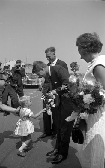 RFK leans down to accept flwoers from a small girl.