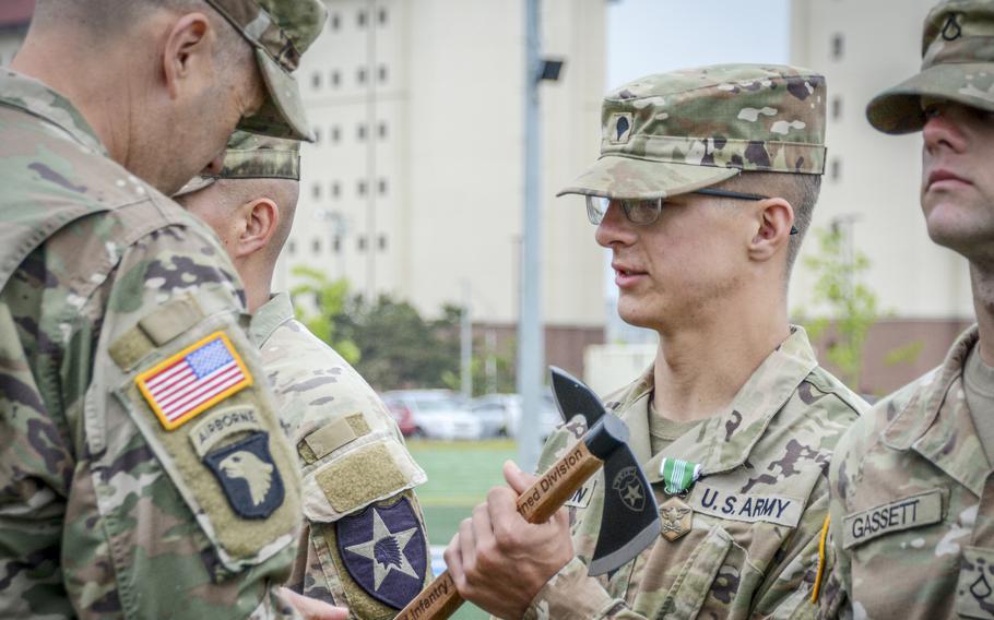 Spc. Seth Wilson, of the 11th Engineer Battalion, 2nd Infantry Division Sustainment Brigade, receives an Army Commendation Medal and a tomahawk trophy during the Best Squad awards ceremony at Camp Humphreys, South Korea, May 6, 2024.