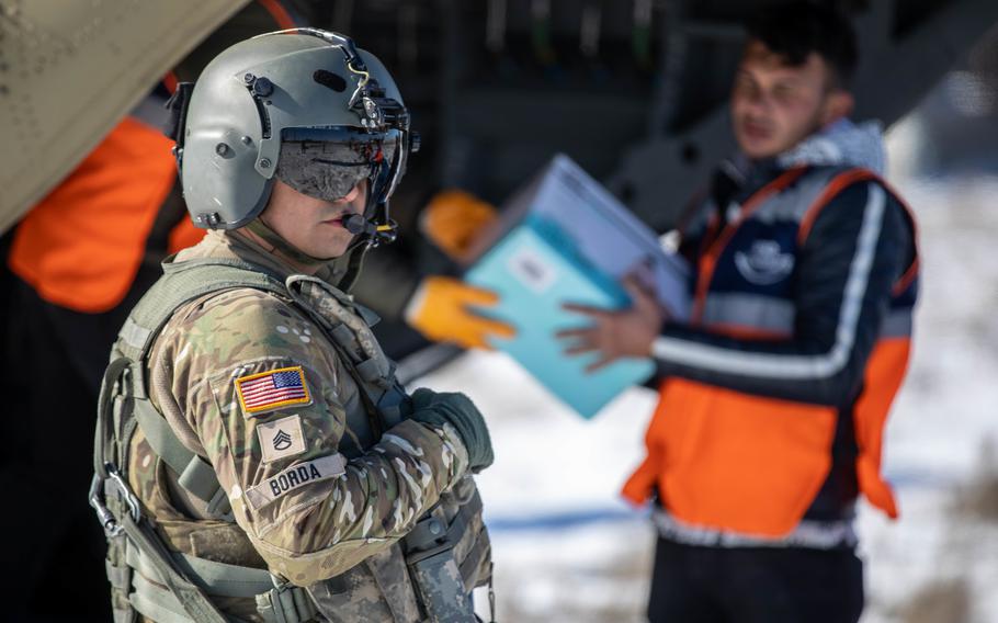 U.S. Army Staff Sgt. Jose Borda, a CH-47F Chinook crew chief, supervises as relief supplies are unloaded from his aircraft in Elbistan, Turkey, on Tuesday, Feb. 14, 2023.