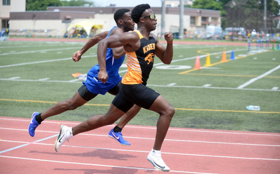 Kadena's Neil Kentish and Yokota's Baron Reed head to the finish of the 100-meter preliminaries.