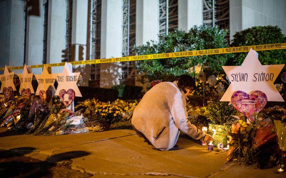 A woman leaves a candle in front of the Tree of Life synagogue after 11 people were killed during a 2018 shooting in Pittsburgh. 