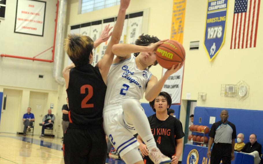 Osan's Adam Rutland collides with E.J. King's Nolan FitzGerald during Monday's Far East Boys Division II pool-play game, won by the Cougars 77-65.