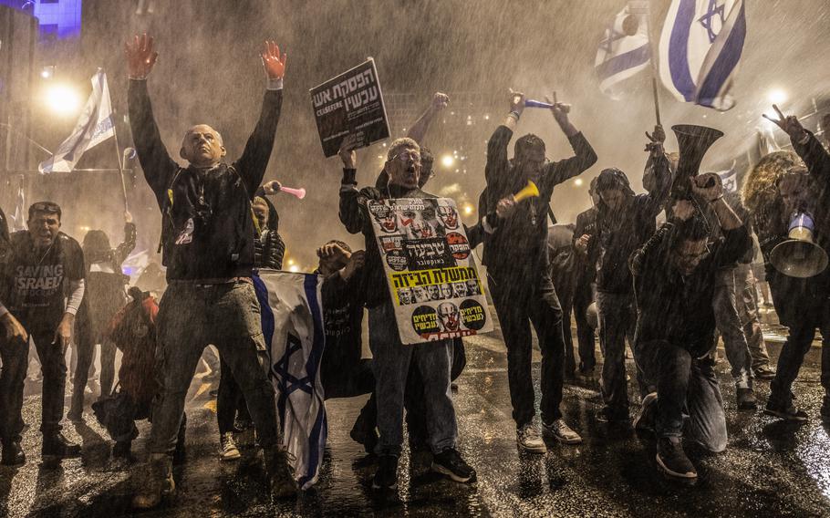 Protesters stand in the spray of police water cannons Saturday in Tel Aviv as they denounce Prime Minister Benjamin Netanyahu’s government and demand a deal to free the hostages in Gaza.