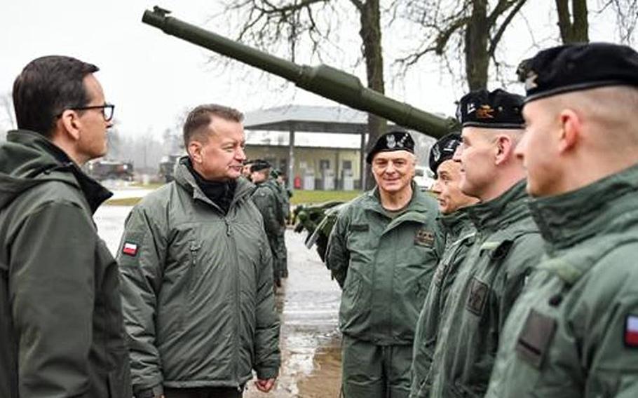 Polish Prime Minister Mateusz Morawiecki, left, and Defense Minister Mariusz Blaszczak meet with crews training on Abrams tanks in Biedrusko, Poland, in 2022. Blaszczak said in a statement June 26, 2023, that 14 Abrams tanks are slated to arrive at a Polish port the following day.
