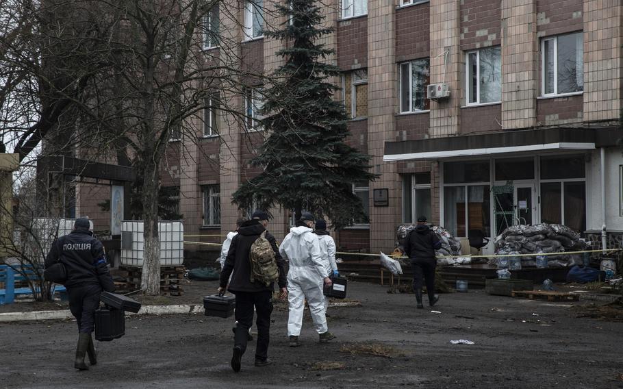 Ukrainian investigators enter a building on April 9 that was occupied by Russian forces. Male corpses that showed signs of torture and execution were found behind the building on April 3, 2022.
