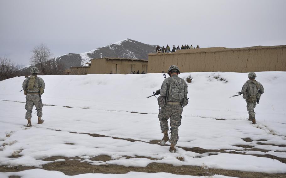 Villagers wait on a rooftop as U.S. soldiers walk into town during a mission in Wardak province. The soldiers got a cool reception in an area where violence has kept civil projects from being completed.