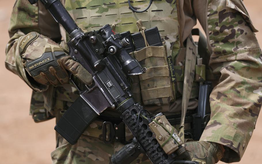 A soldier in uniform holds a gun.
