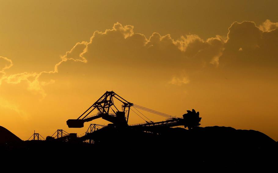 A stacker-reclaimer operates next to stockpiles of coal at the Newcastle Coal Terminal in Newcastle, New South Wales, Australia, on March 26, 2021. 