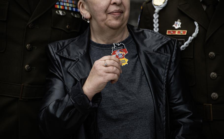 Marina Hilbert holds a challenge coin presented to her by U.S. Army Col. Deon Maxwell at the Husterhöh Kaserne audio guide unveiling in Pirmasens, Germany, on Wednesday, May 8, 2024.