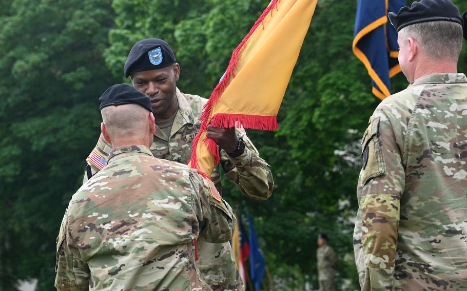 Brig. Gen. James Smith, the incoming leader of the 21st Theater Sustainment Command, takes the unit colors from U.S. Army Europe and Africa commander Gen. Christopher Cavoli at the 21st TSCs change of command ceremony at Daenner Kaserne, Kaiserslautern, Germany, June 8, 2021. At right is the outgoing commander, Maj. Gen. Christopher Mohan.