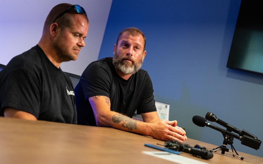 Two men sit down at a media table.
