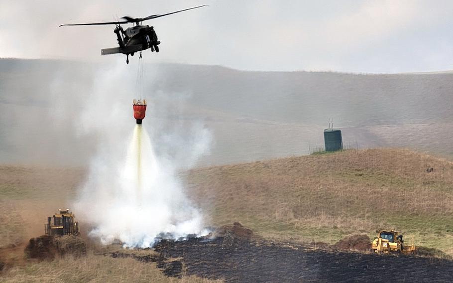An Army HH-60 Black Hawk from the 25th Combat Aviation Brigade, 25th Infantry Division, drops water on a fire near the Pohakuloa Training Area, Hawaii, July 31, 2021.