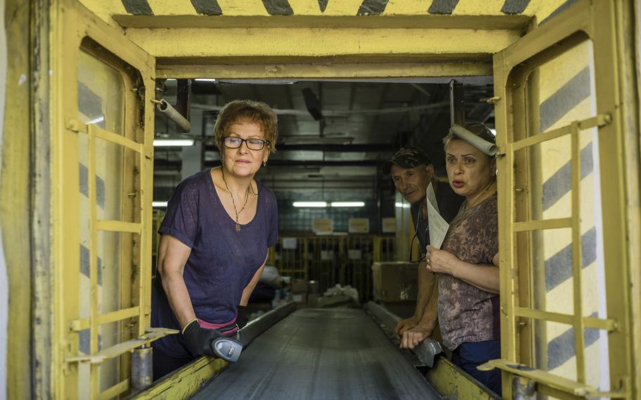 Workers sort mail at a postal warehouse. 