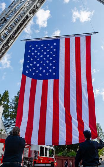 Grass Valley, Calif., firefighters raise a flag over the street in celebration of the memorial service of retired Lt. Cmdr. Lou Conter.