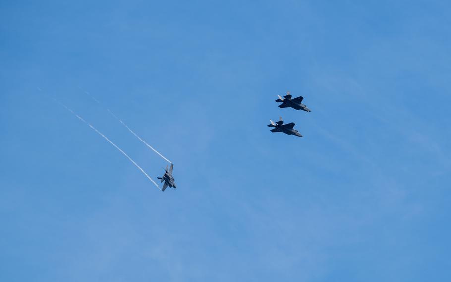 Three fighter jets seen flying against a blue sky.