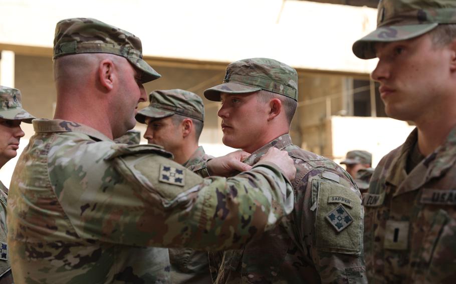 Lt. Col. Gregory Polk, the 299th Bridge Engineer Battalion commander, pins the Combat Action Badge on to a soldier's uniform during a ceremony at the coalition base Union III in Baghdad, March 24, 2022. Members of from the 299th Bridge Engineer Battalion and 4th Battalion, 9th Infantry, received the award for their response to an enemy attack on the installation. 