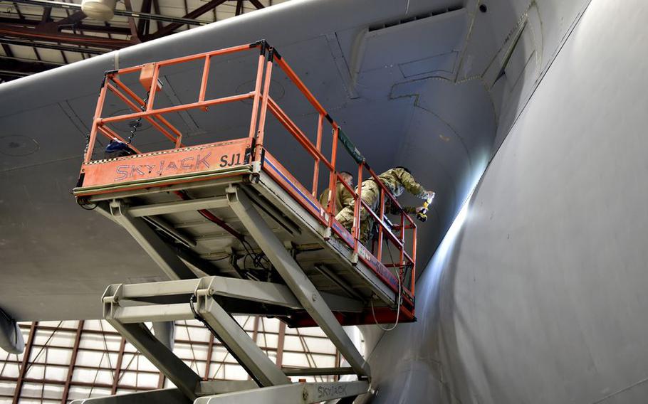 Technicians use flashlights to examine a possible fluid leak on a C-5M Super Galaxy  in a maintenance hangar at Westover Air Reserve Base in Chicopee, Mass.  