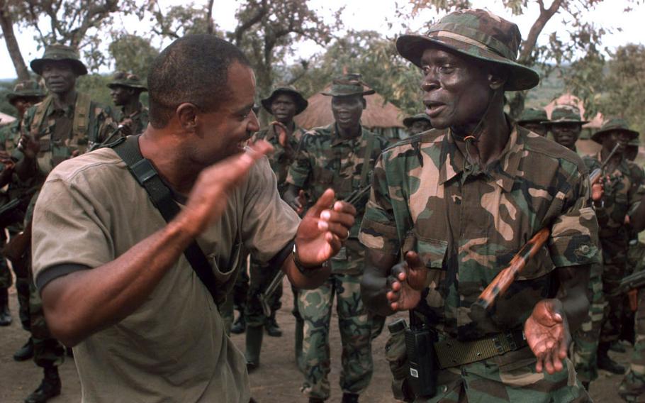 Staff Sgt. Robert Parker (left) joins Ugandan soldiers in singing African military songs. Parker is a Green Beret with the 3rd Battalion, 3rd Special Forces Group out of Fort Bragg, N.C., who is spending 60 days in Uganda teaching peacekeeping skills to local troops as part of a U.S.-backed program called the African Crisis Response Initiative.