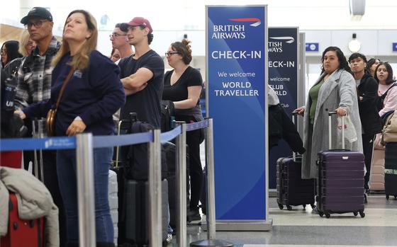 Travelers stand in line with their luggage.