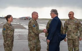 A man in a suit shakes hands with another man in a Space Force uniform.