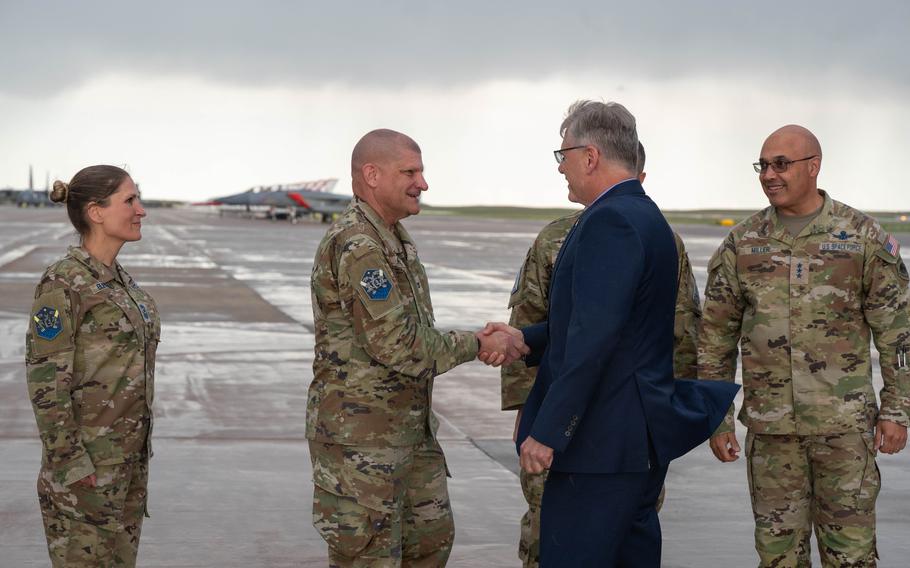 A man in a suit shakes hands with another man in a Space Force uniform.