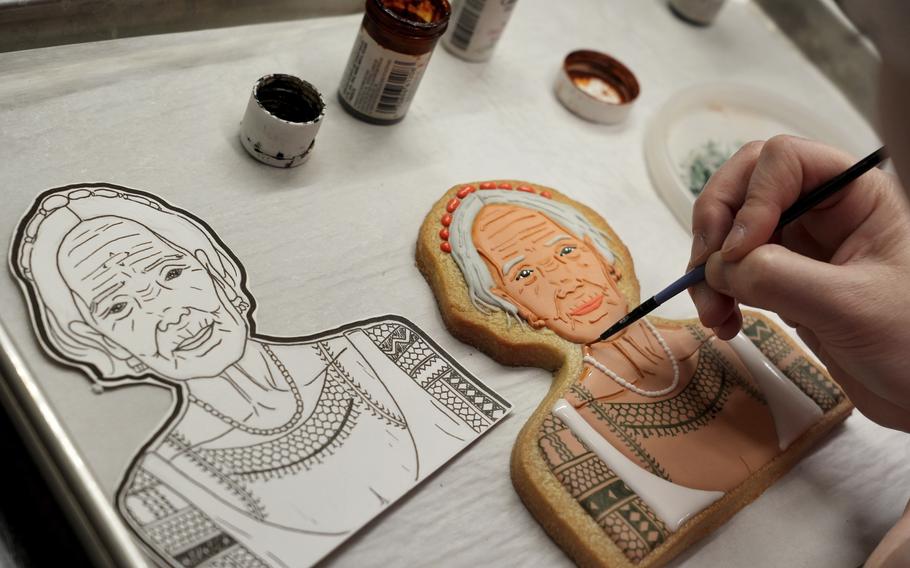 Jasmine Cho works on a cookie portrait of Filipina mambabatok tattoo artist Apo Whang-Od in Pittsburgh, Pa., May 3. Cho needs between four and six hours for one portrait. She draws the cookie face by hand, fills it in with icing and then lets it dry.