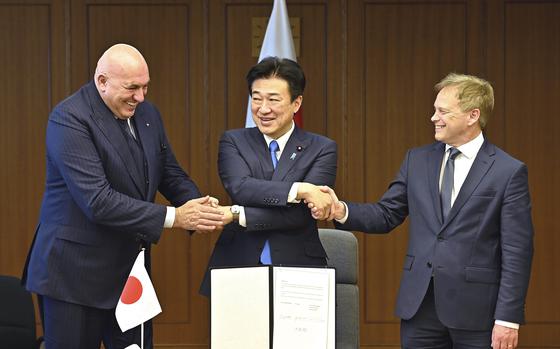 Britain's Defense Minister Grant Shapps, right, Italy's Defense Minister Guido Crosetto, left, and Japanese Defense Minister Minoru Kihara, center, shake hands after a signing ceremony for the Global Combat Air Programme (GCAP) at the defense ministry, Dec. 14, 2023, in Tokyo, Japan. Japan’s Cabinet on Tuesday, March 26, 2024, approved a plan to sell future next-generation fighter jets that it’s developing with Britain and Italy to other countries, in the latest move away from the country’s postwar pacifist principles.