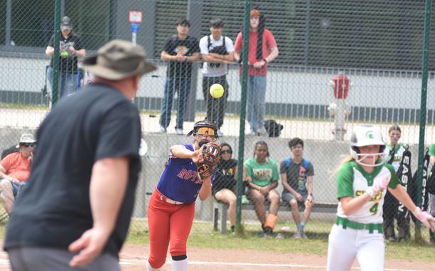 SHAPE assistant coach Mike Hurd shouts encouragement as Colie Meyer races to first to try to beat the throw of Ramstein pitcher Kelsey Moya on Wednesday, May 21, 2025, on the opening day of the DODEA-Europe Division I softball championships at Kaiserslautern, Germany.