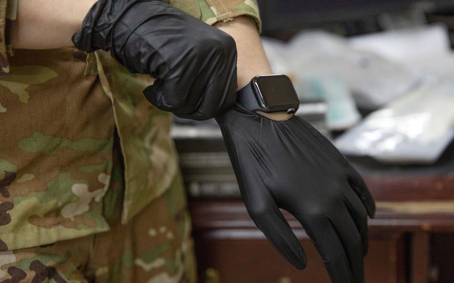 Army Sgt. Kayla Sampson pulls on a medical glove while training at Camp Buehring, Kuwait, July 30, 2020.