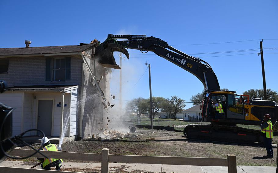 Excavator knocking down the side of a house. 