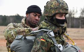 A U.S. Army paratrooper assigned to the 173rd Airborne Brigade inspects the parachute of a German paratrooper at Grafenwoehr Training Area in 2018. The Pentagon needs a new method for measuring whether countries in Europe and Asia are carrying their fair share of the security burden, according to a new Rand Corp. study.