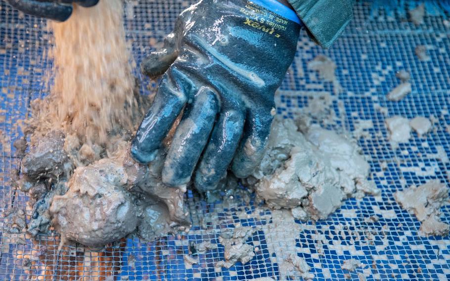 A U.S. service member supporting a mission by the Defense POW/MIA Accounting Agency sifts through clay excavated at a site in Wistedt, Germany, Oct. 30, 2023.