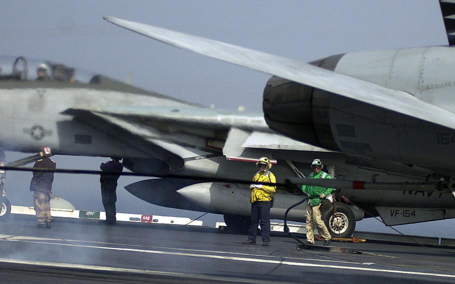 Crewmembers watch as an F-14 Tomcat snags an arresting wire on the flight deck of the USS Kitty Hawk on Monday, April 15, 2002.