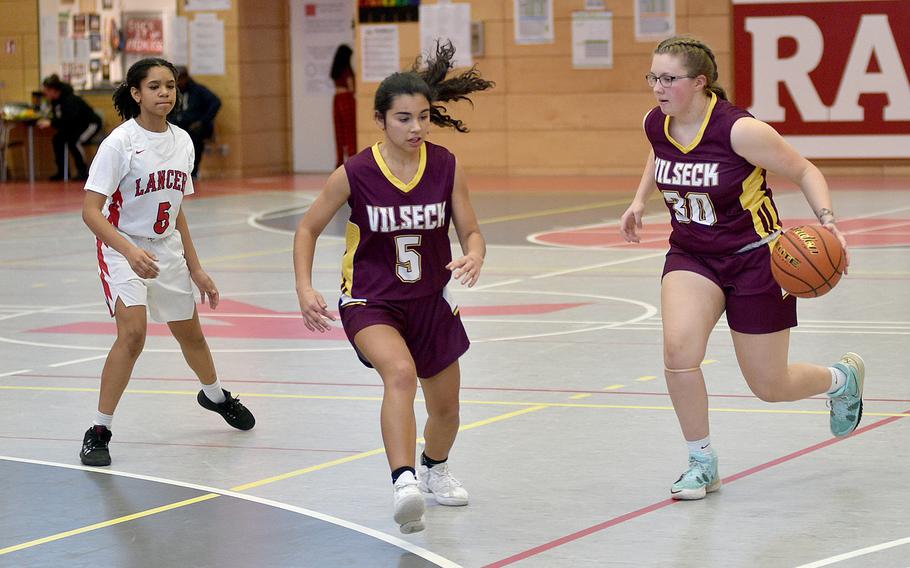 Vilseck's Morgan Robbine, right, dribbles while teammate Jayslin Santellano runs to the corner during the Falcons' showdown with Lakenheath on Saturday at Kaiserslautern High School in Kaiserslautern, Germany. Following the action is the Lancers' Alanah Melvin.