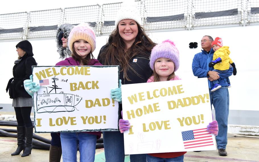 A USCGC Hamilton crew member's family displays signs at the pier in North Charleston, S.C., Dec. 21, 2022, after Hamilton completed a 94-day deployment in the Baltic Sea, in support of U.S. 6th Fleet.