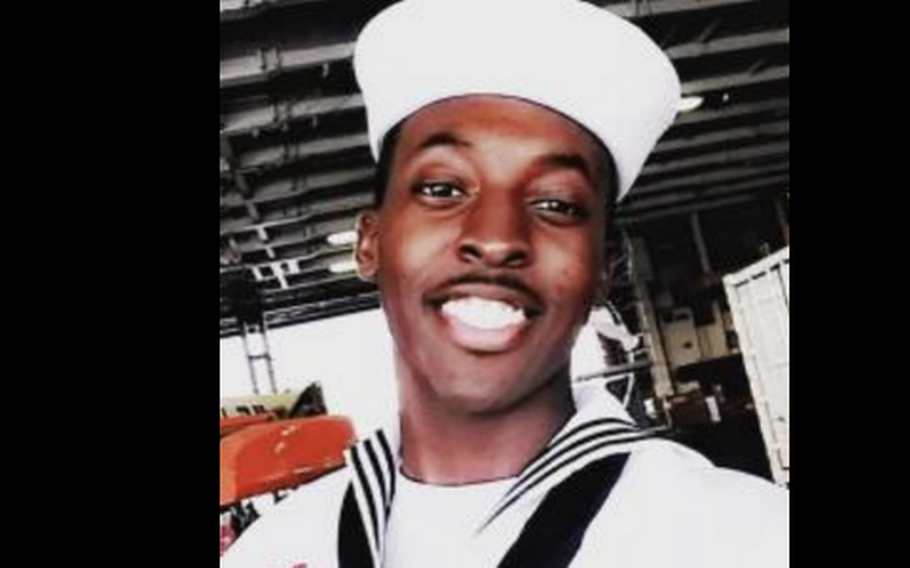 A Navy sailor in uniform smiles.