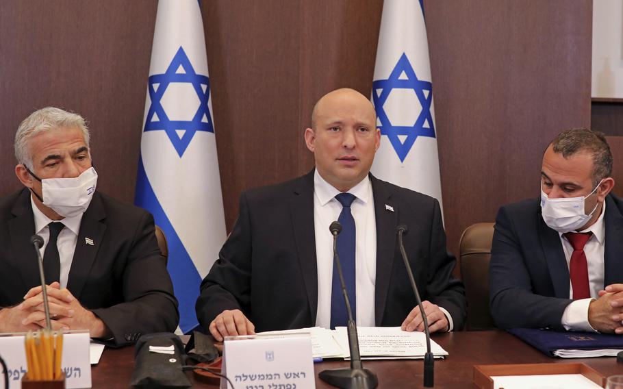 Israeli Prime Minister Naftali Bennett, center, chairs a weekly cabinet meeting, at the prime minister’s office in Jerusalem, Sunday, Dec. 5, 2021.  Bennett on Sunday urged world powers to take a hard line against Iran in negotiations to curb the country’s nuclear program, as his top defense and intelligence officials headed to Washington amid the flailing talks. 
