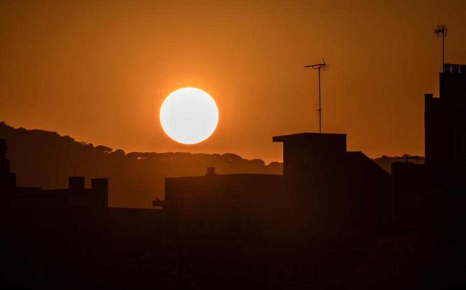 The sun sets beyond residential rooftops in Mataro, Spain, on Wednesday, Aug. 23, 2023.