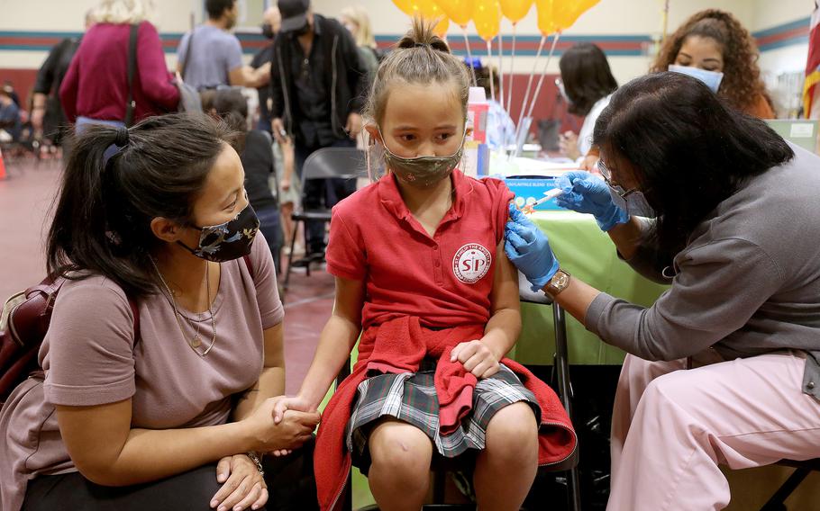 Nicole Fahey sits with her daughter Adelina, 6, as she receives the pediatric Pfizer-BioNTech vaccination from nurse Shirley Alfonso at Eugene A. Obregon Park in Los Angeles.