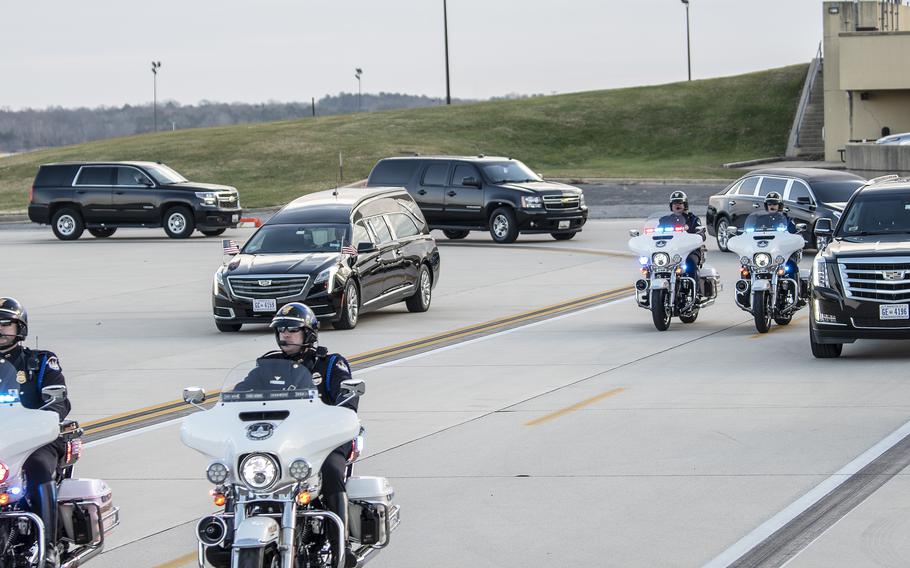 A police-escorted motorcade arrives at Joint Base Andrews, Md., on Friday, Dec. 10, 2021, as a hearse carries the burial casket of WWII veteran and former Kansas Sen. Bob Dole.
