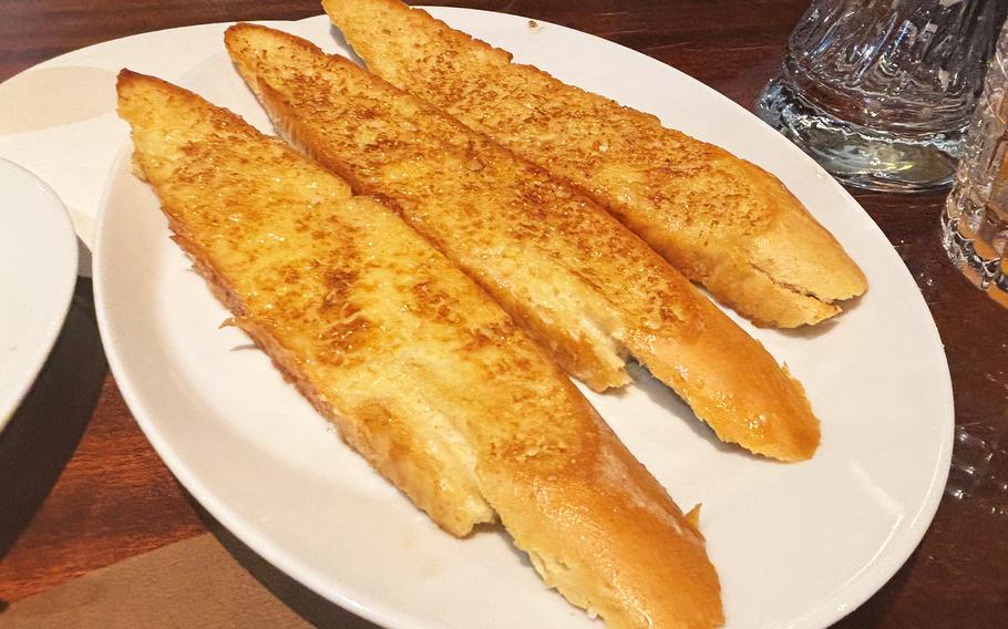 Three pieces of garlic bread on a white plate.